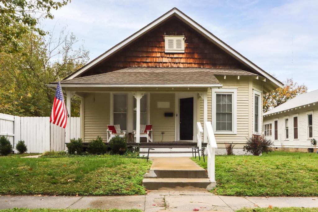 Uma casa com uma bandeira americana no alpendre. em The Porter Pearl Centrally Located Joplin Home! em Joplin