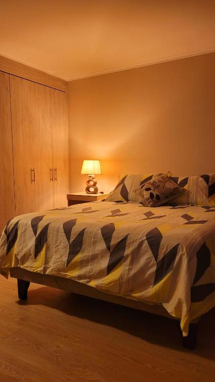 a bedroom with a large bed with a lamp on it at dpto x día chillan 1411 in Chillán