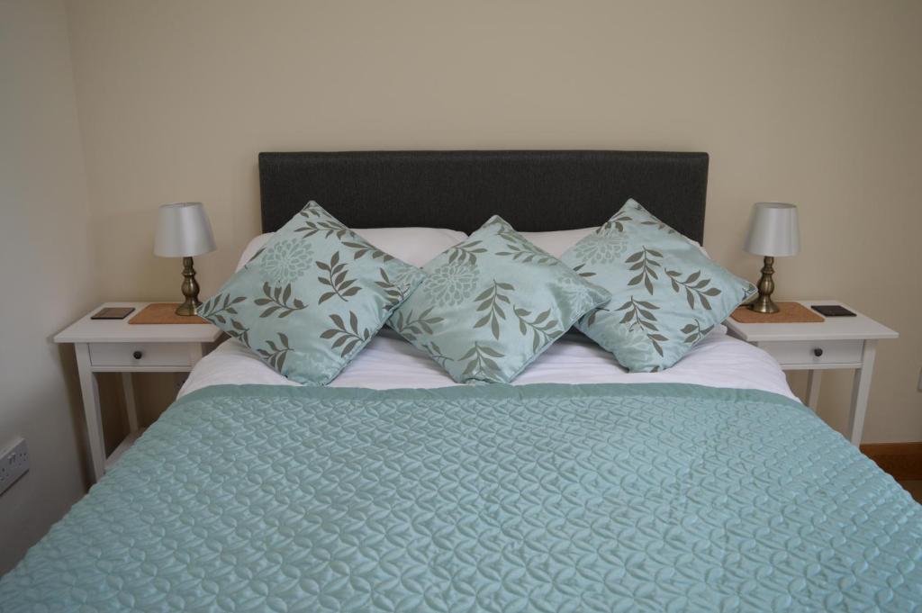 - un lit avec une couette et des oreillers bleus dans l'établissement Wardie Garden Cottage, à Édimbourg