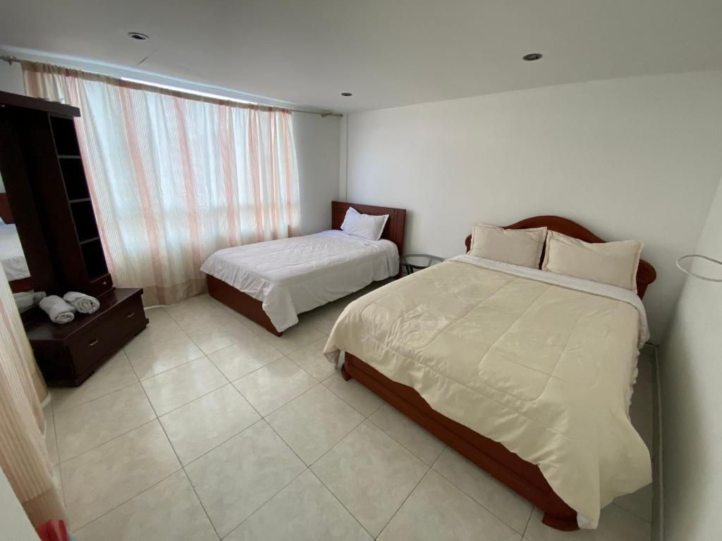 ボゴタにあるStay In Bogotaのベッド2台と窓が備わるホテルルームです。