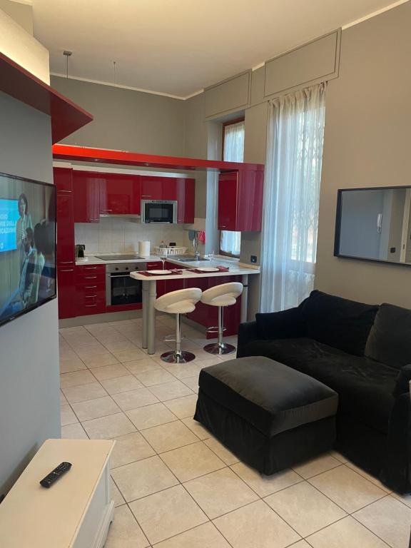 ein Wohnzimmer mit einem schwarzen Sofa und einer Küche in der Unterkunft Residenza Parco in Segrate