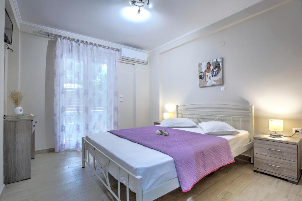 a bedroom with a large bed with a purple blanket at Neapolis Apartment in Lefkada
