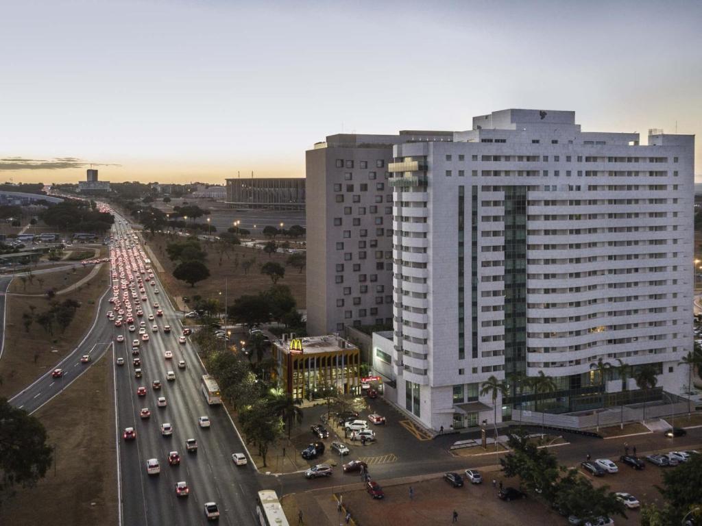 un grand bâtiment blanc avec circulation sur une autoroute dans l'établissement Flat no Brasília Lider, 14º Andar, à Brasilia