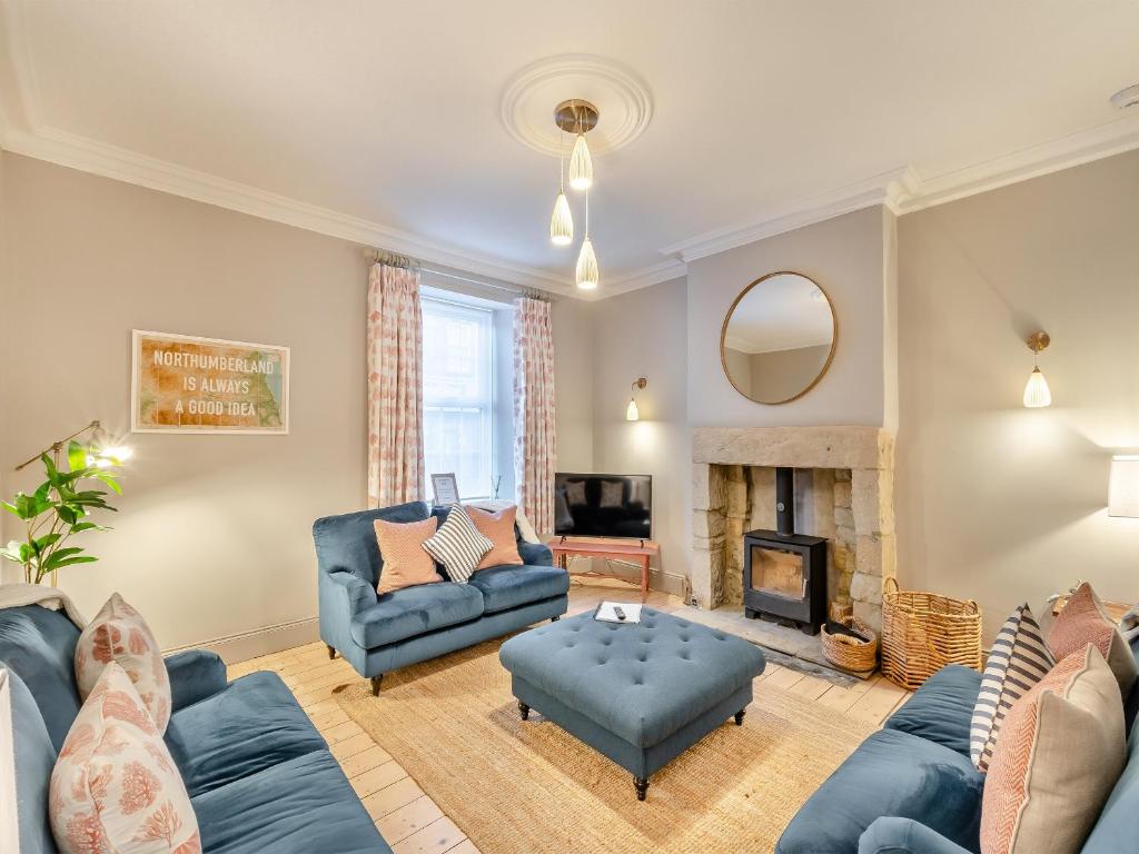 a living room with blue furniture and a fireplace at Coral Cottage in Amble