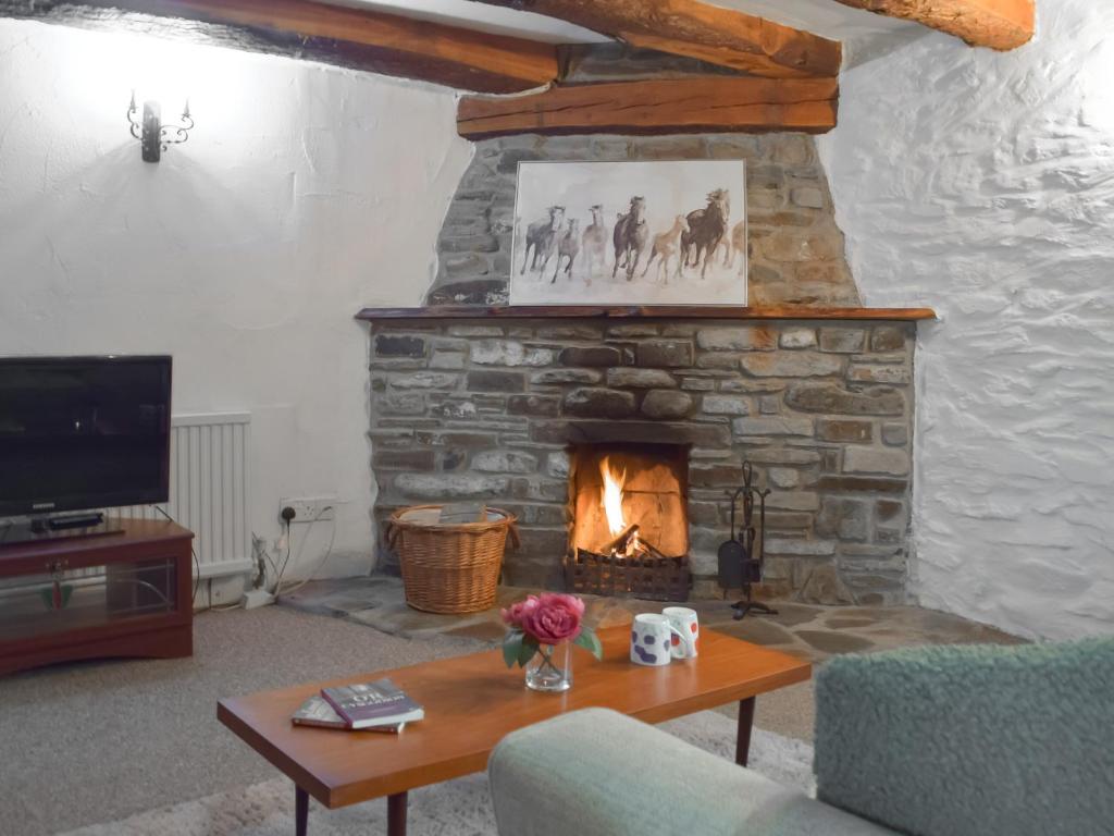 a living room with a stone fireplace and a table at Ty Ceffylau - Uk46190 in Llanybydder