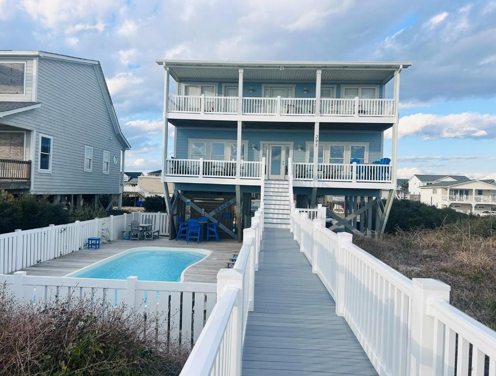 a house with a boardwalk leading to a swimming pool at Sunny Times in Holden Beach