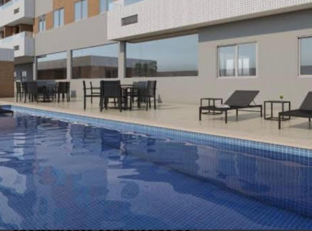 una piscina con mesas y sillas en un edificio en Apartamento Praia do Futuro mobiliado, en Fortaleza