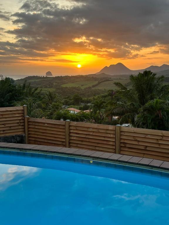 a swimming pool with a sunset in the background at Domaine Madinina Dream in Sainte-Luce