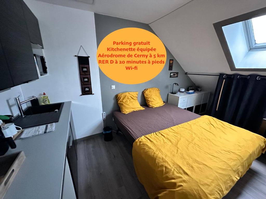 una camera da letto con un letto con un piumone giallo e un lavandino di NID DOUILLET INDEPENDANT a La Ferté-Alais