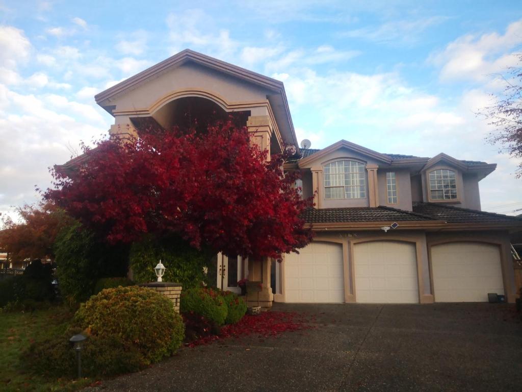 a house with two garage doors and a red tree at V.I.P. CLUB in Surrey