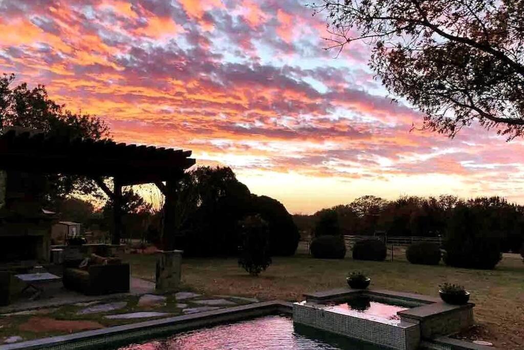 una puesta de sol sobre un estanque en un patio en Beautiful Farmhouse w/ pool on 6 acres ranch, en Aubrey
