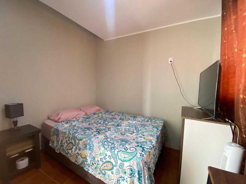 Dormitorio pequeño con cama y TV en La casa de los Viajeros, en Huarmey