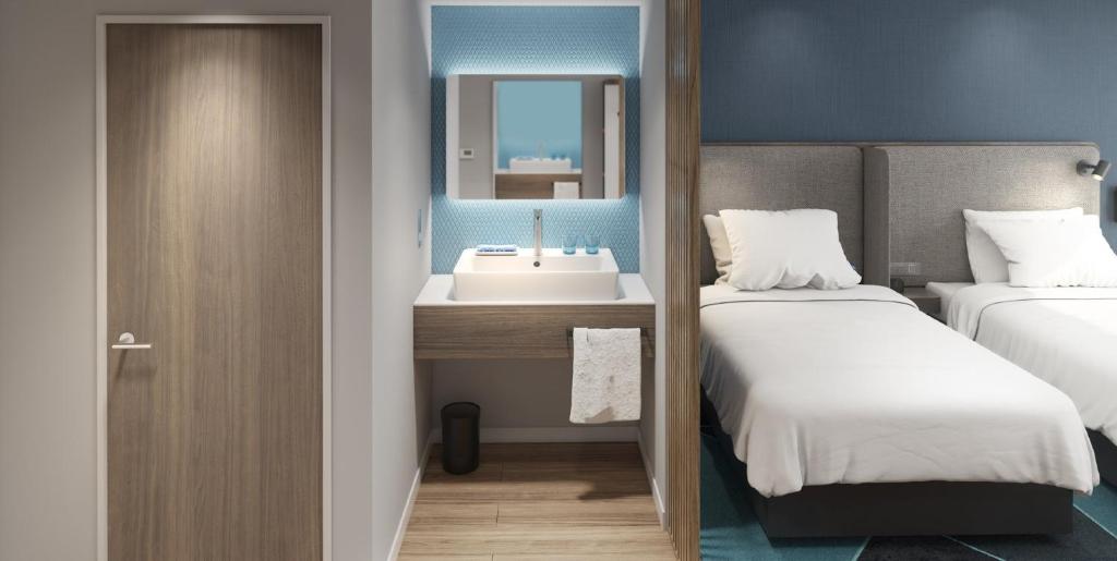 a bathroom with two beds and a sink and a mirror at Holiday Inn Express Pingchang, an IHG Hotel in Bazhong