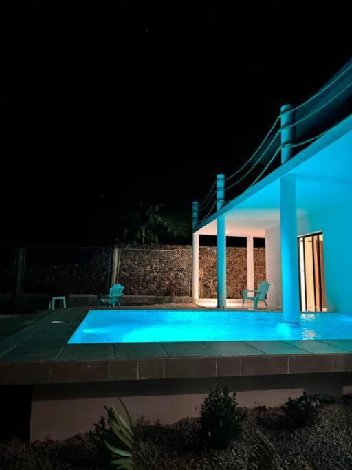 una casa iluminada con piscina por la noche en Villa Sunrise RD, en Las Galeras