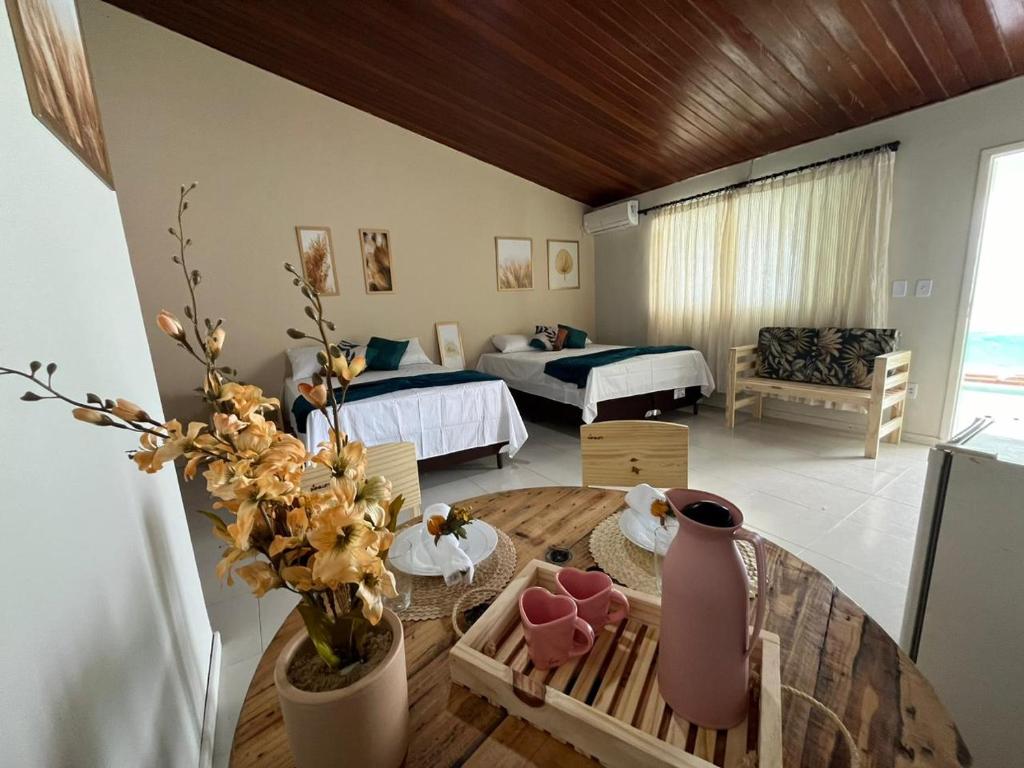 a living room with a table and a room with two beds at Sam Day Suites in Natal