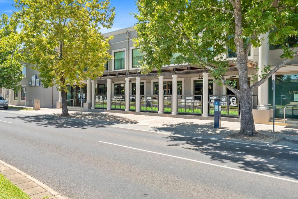 an empty street in front of a building with trees at Sherbourne Terrace Hotel in Shepparton