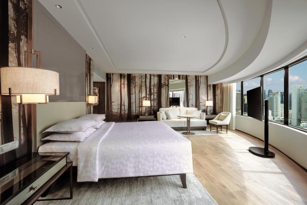 a bedroom with a large bed and a living room at JW Marriott Hotel Bangkok in Bangkok