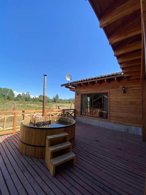 una cabina dotata di terrazza in legno con vasca idromassaggio. di Cómodas y acogedoras cabañas a Huépil