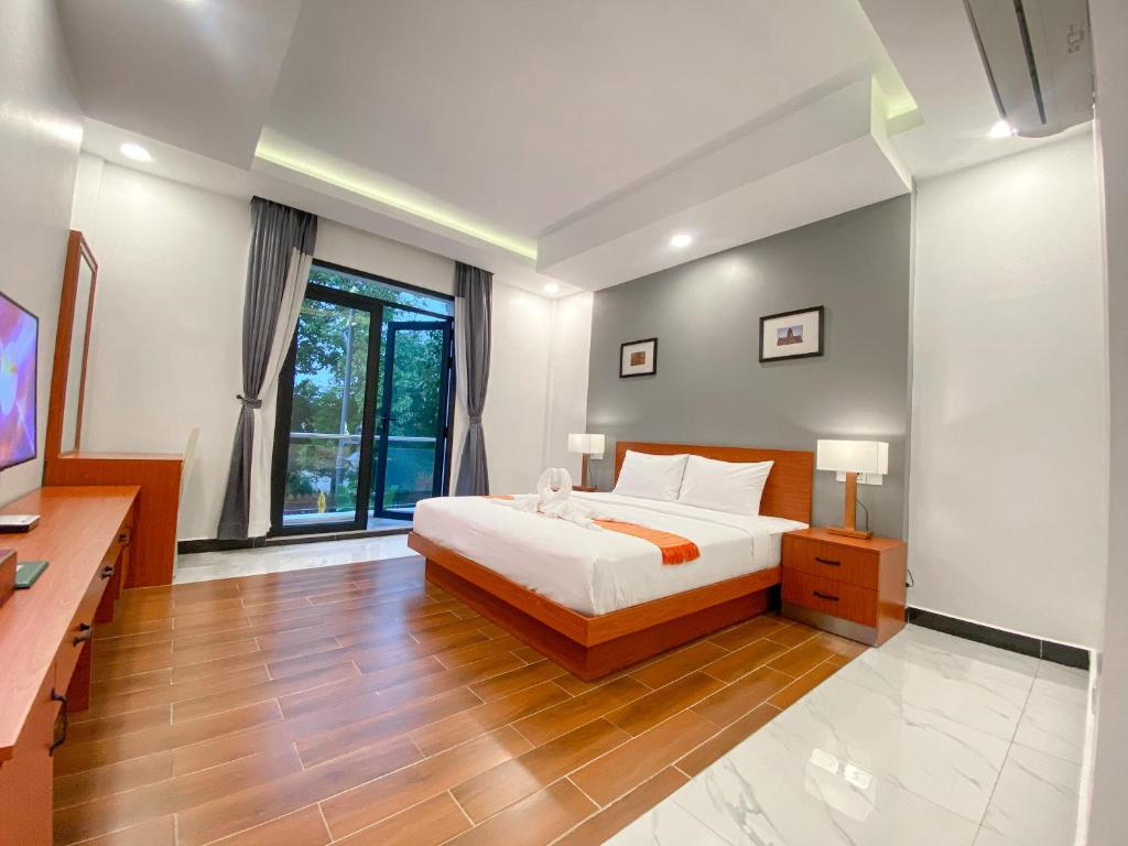 een grote slaapkamer met een bed en een televisie bij ANGKOR SIVUTHA HOTEL in Siem Reap