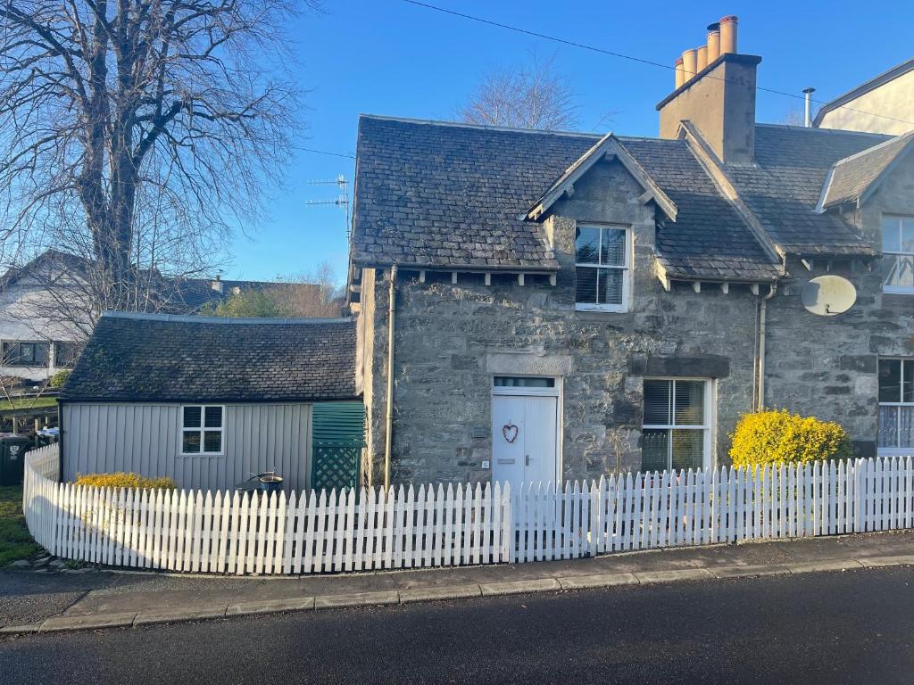 een oud stenen huis met een wit hek bij Moulin Cottage in Moulin