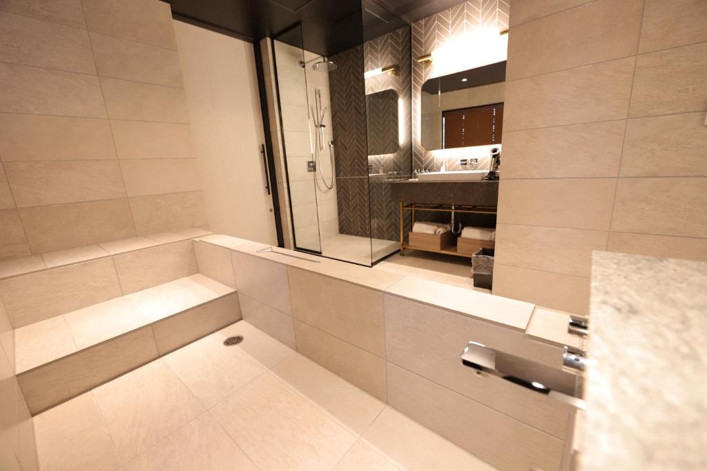 a bathroom with a shower with a sink and a mirror at Spa World HOTEL&RESORT in Osaka