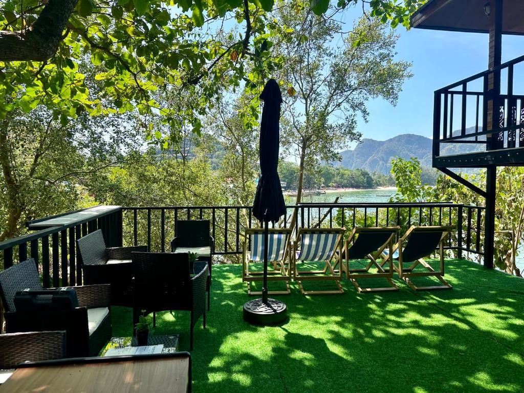 a deck with chairs and an umbrella on the grass at Sweed Dee Seaview Hostel in Phi Phi Islands