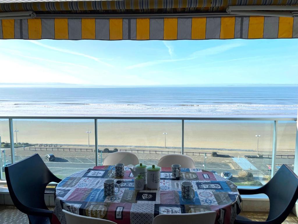 - une table avec des chaises et une vue sur l'océan dans l'établissement Magnifique appart rénové 2 chambres, face à la mer - 3 étoiles, garage privé, proche plage et commerces - FR-1-323-329, à Saint-Jean-de-Monts