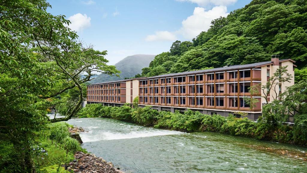 a building next to a river next to a mountain at Hotel Indigo Hakone Gora by IHG in Hakone