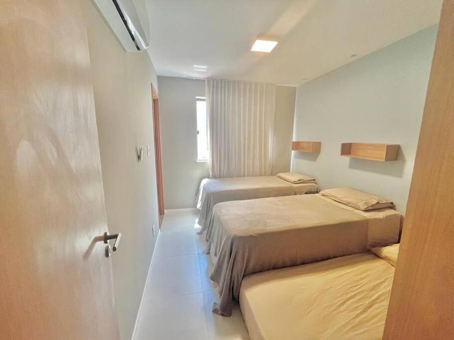 Zimmer mit 2 Betten und einer Tür zu einem Schlafzimmer in der Unterkunft Luxuoso Village em Guarajuba in Guarajuba