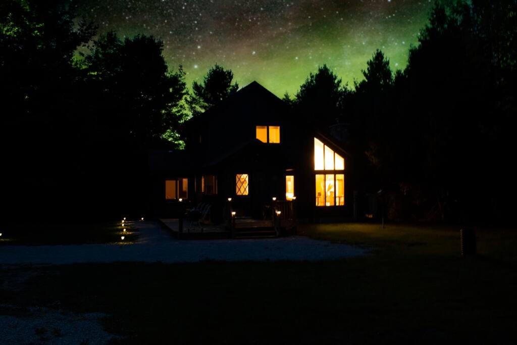 a house at night with a green sky at Secret Hideaway 4BED Lakefront w/Hotub in Sheshegwaning