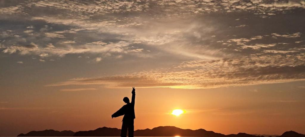un hombre de pie con las manos arriba en frente de la puesta de sol en ImagineWestOcean - Vacation STAY 15912, en Suo Oshima