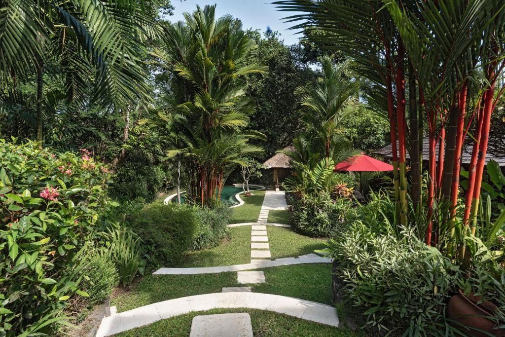 un jardín con palmeras y una pasarela en Villa Pangi Gita, en Canggu