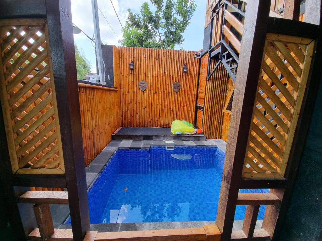 a swimming pool in a backyard with a wooden fence at Suci's Friendly Appartment in Mataram