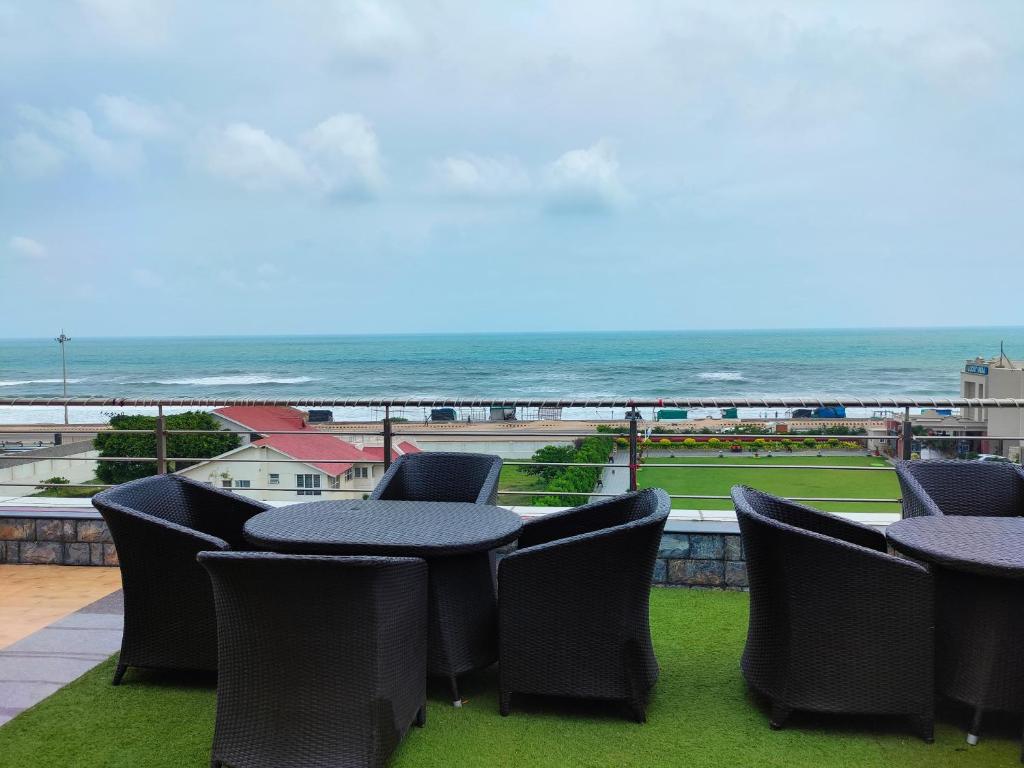 a balcony with tables and chairs and the ocean at Hotel Sagar Kanya INN in Puri