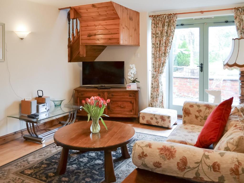 a living room with a couch and a tv and a table at Clover Cottage - Uk46269 in Tetney