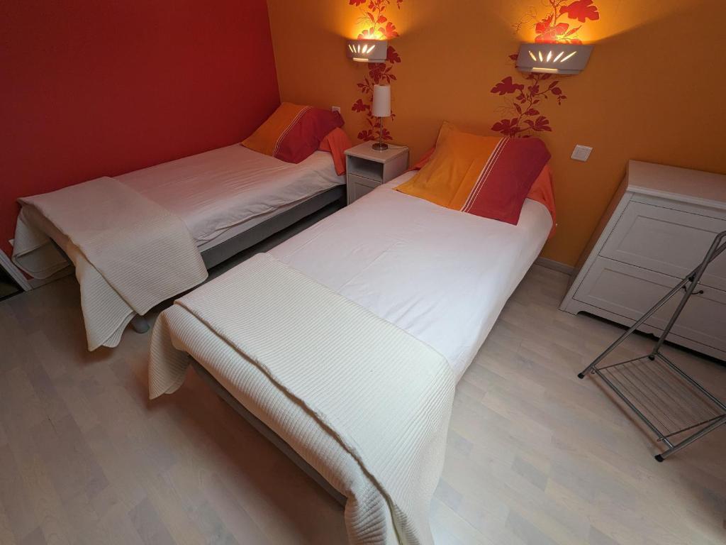two twin beds in a room with orange walls at Guestroom Arbigny-sous-Varennes, 2 pièces, 4 personnes - FR-1-611-72 