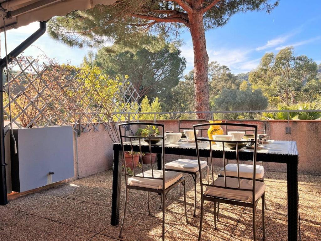 une table et quatre chaises assises sur une terrasse dans l'établissement Duplex avec piscine, 3 pièces cabine, 6 couchages, terrasses et parking proche plage - Le Lavandou - FR-1-251-536, au Lavandou