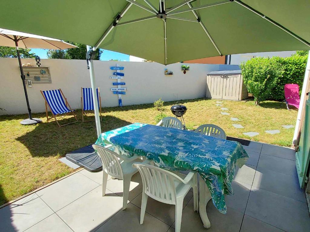 - une table et des chaises avec un parasol dans la cour dans l'établissement Maison avec piscine, tennis et aire de jeux à 950m de la plage de sable fin - Saint-Vincent-sur-Jard - FR-1-336-145, à Saint-Vincent-sur-Jard