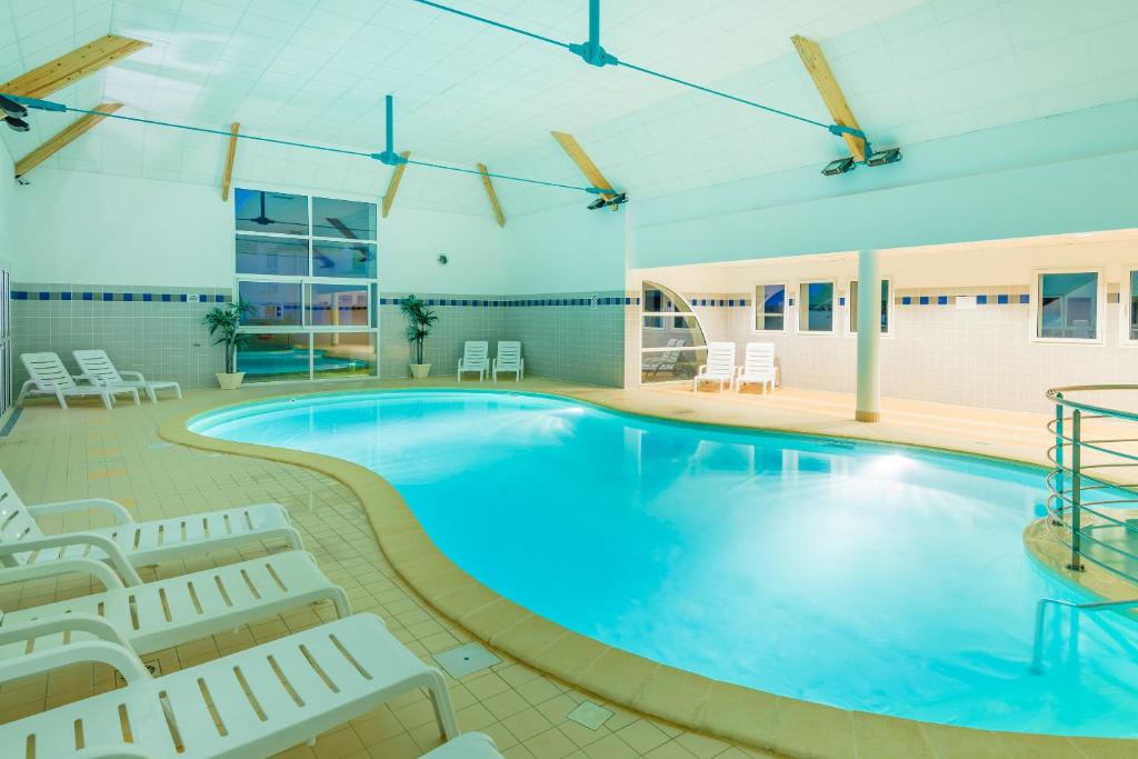 una grande piscina con sedie e sedie in un edificio di Lagrange Vacances Les Jardins Renaissance ad Azay-le-Rideau