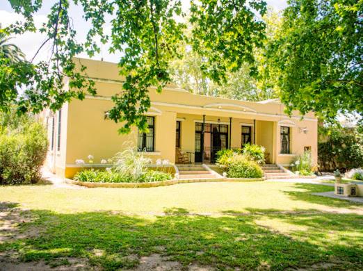 une maison jaune avec des arbres et une cour dans l'établissement Hotel Boutique Villa Rosarito, à Villa del Totoral