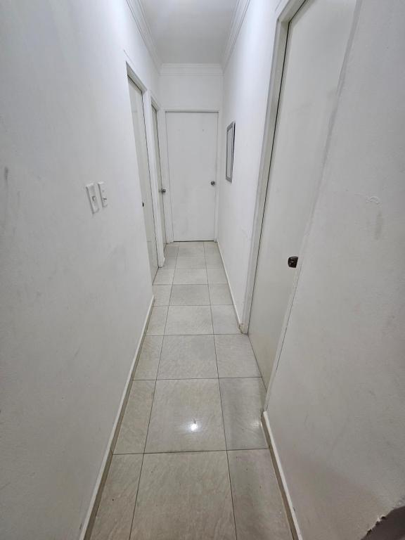 a long hallway with white walls and a tile floor at Apartamento frente malecón SD este in La Francia