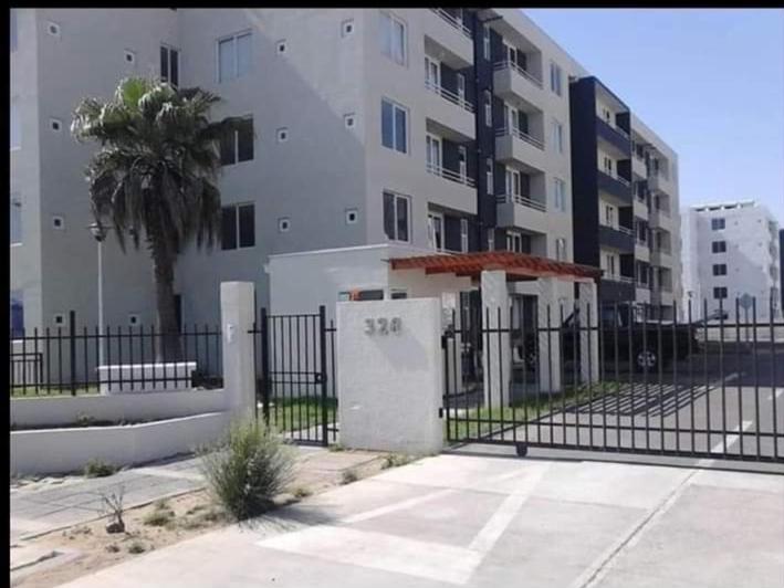 una valla frente a un edificio con una palmera en Departamento verano la serena en La Serena