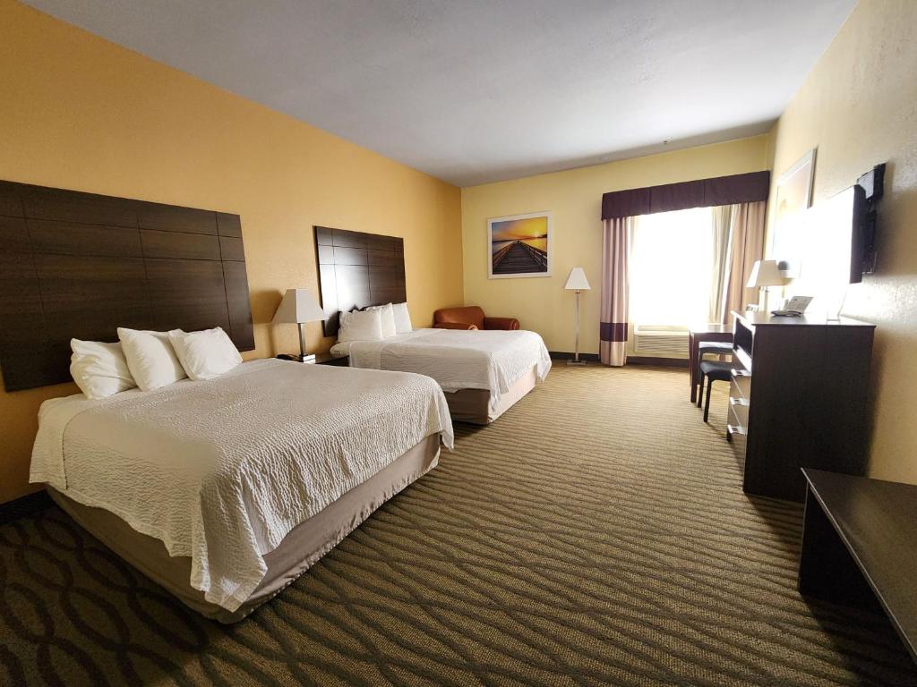 a hotel room with two beds and a desk at Days Inn & Suites by Wyndham Pasadena in Pasadena