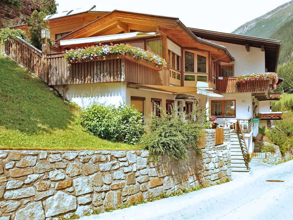 ein Haus auf einem Hügel mit einer Steinmauer in der Unterkunft Ferienwohnung Mühlmann in Außervillgraten