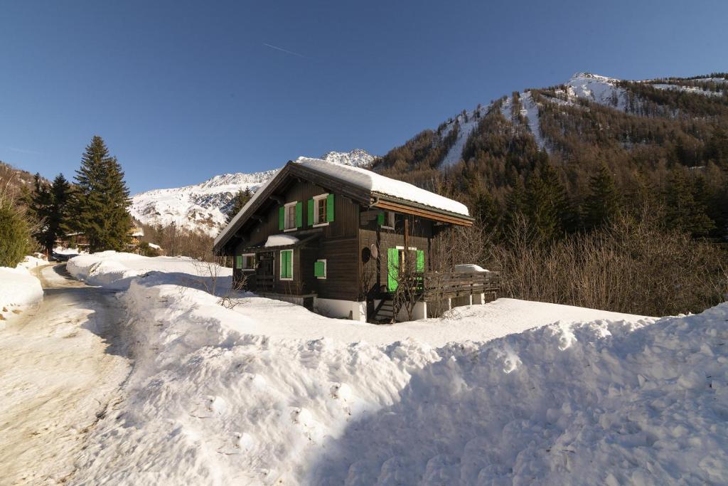 a small house in the snow in front of a mountain at Chalet L’eau vive - Happy Rentals in Chamonix-Mont-Blanc