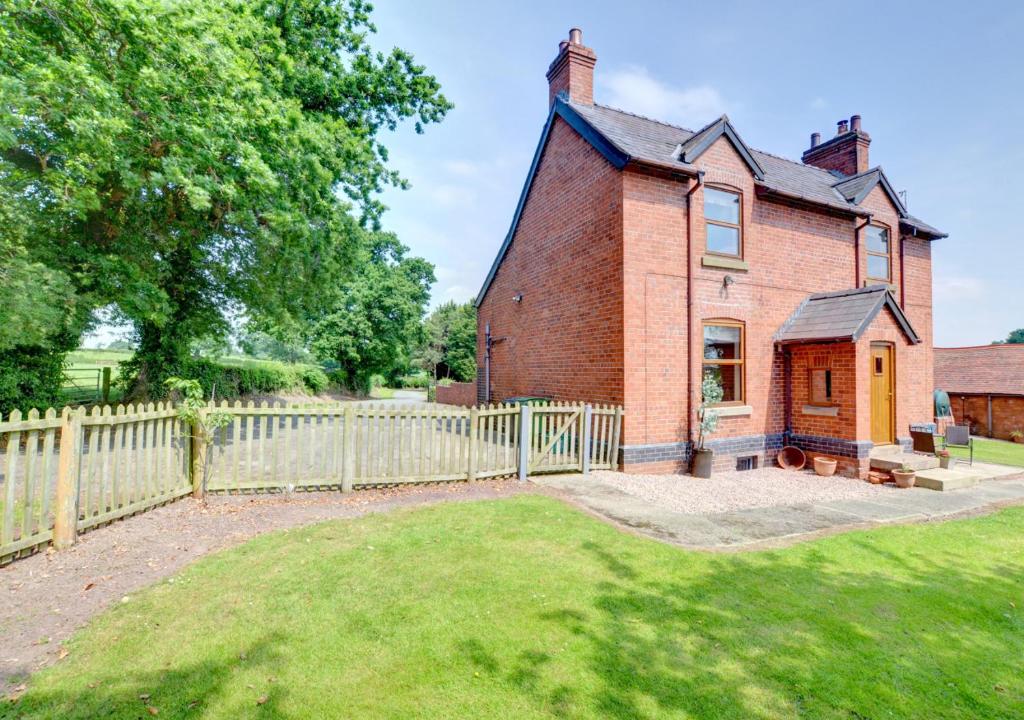 an old brick house with a fence and a yard at The Old Farmhouse in Ruabon