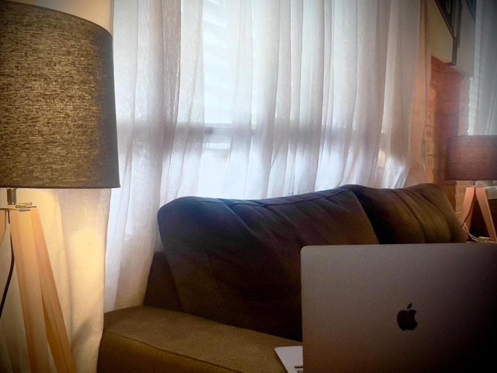 an apple laptop sitting on a couch next to a window at The Ocean Street House in Budgewoi