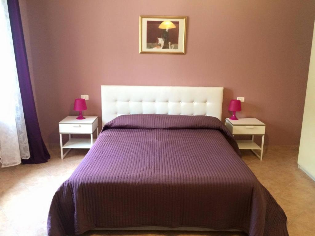 a bedroom with a bed with purple sheets and two night stands at La Piazza B&B in Vercurago