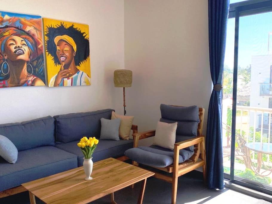 a living room with a blue couch and a painting at Stylish flat with balcony & pool at Paje Beach in Paje