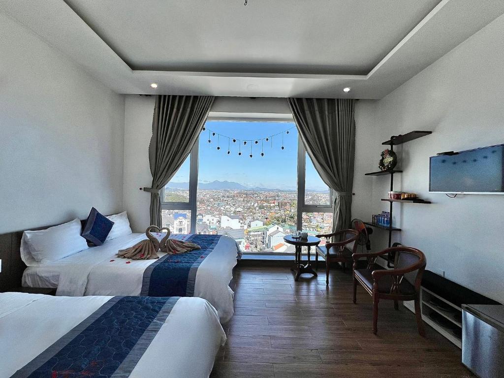 una camera d'albergo con due letti e una grande finestra di Cosy Hotel & Apartment Dalat a Da Lat
